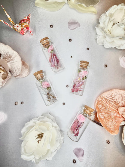 Mini origami cranes and a ribbon rose in a corked glass bottle