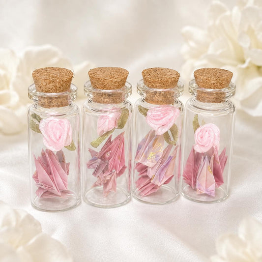 Mini origami cranes and a ribbon rose in a corked glass bottle