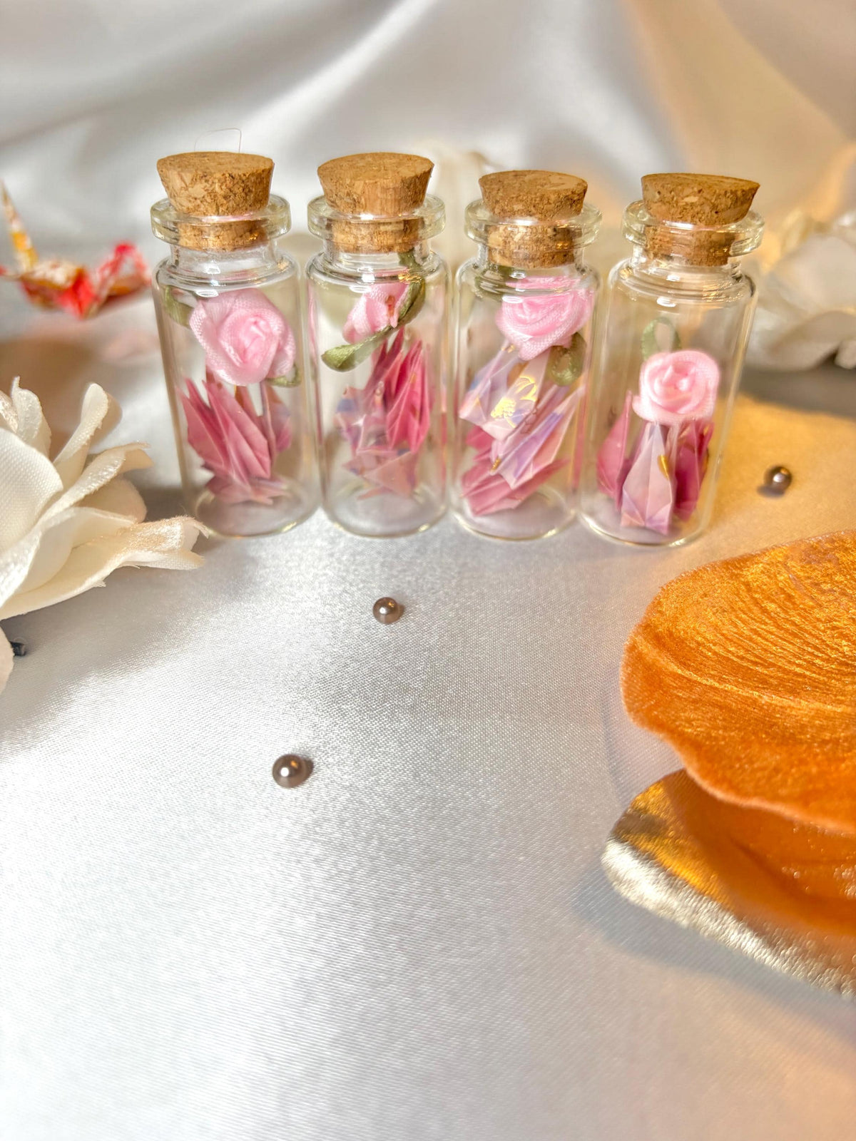 Mini origami cranes and a ribbon rose in a corked glass bottle