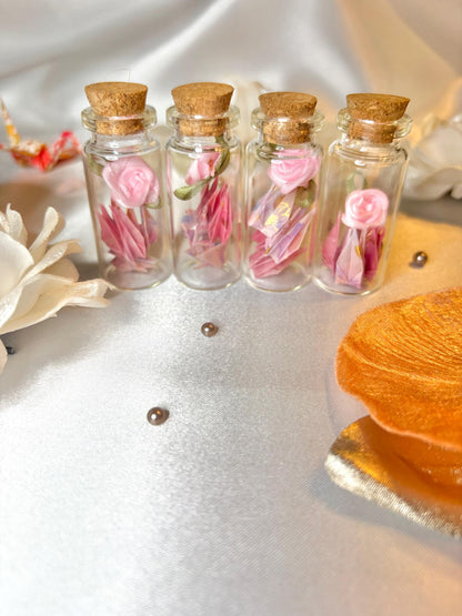 Mini origami cranes and a ribbon rose in a corked glass bottle