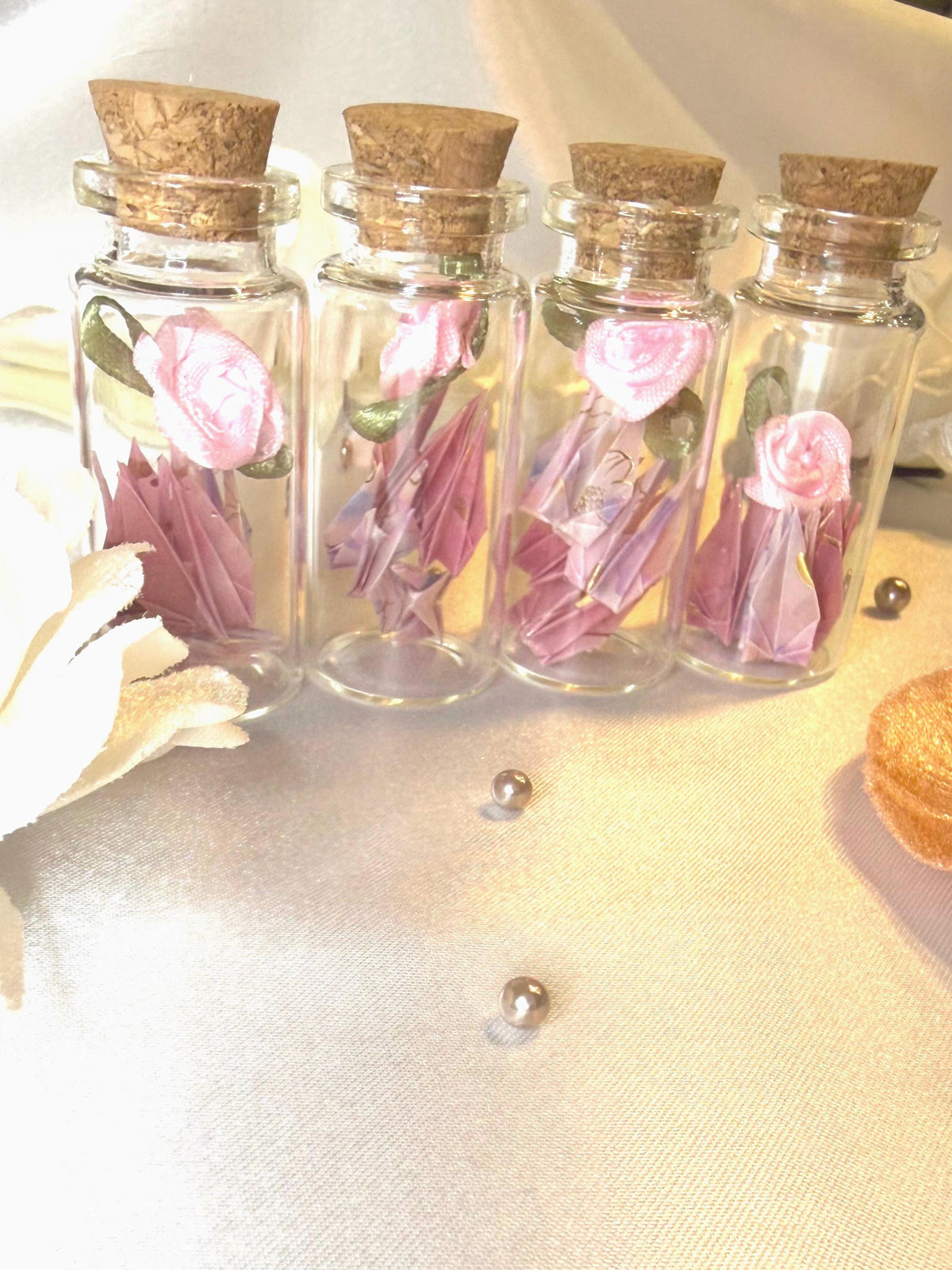 Mini origami cranes and a ribbon rose in a corked glass bottle